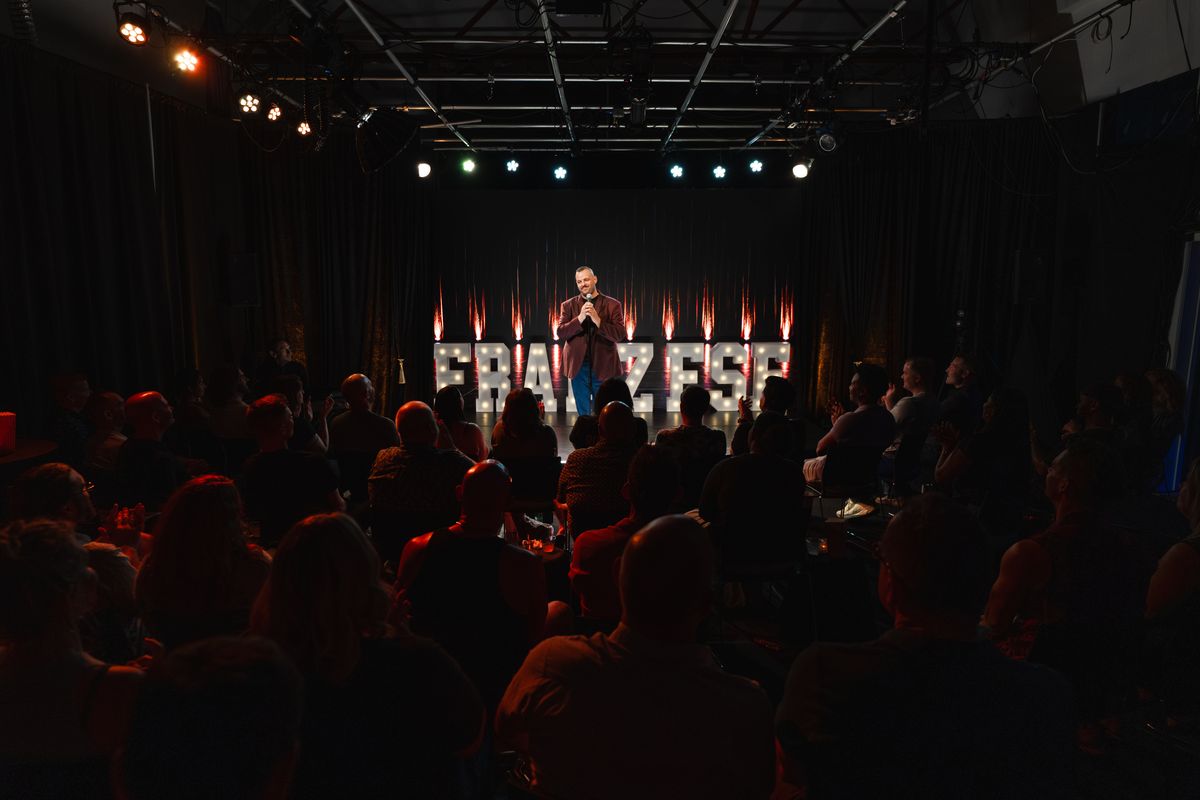 A wide view of the sold-out room at Studio C, Daniel on stage in front of the FRANZESE marquee