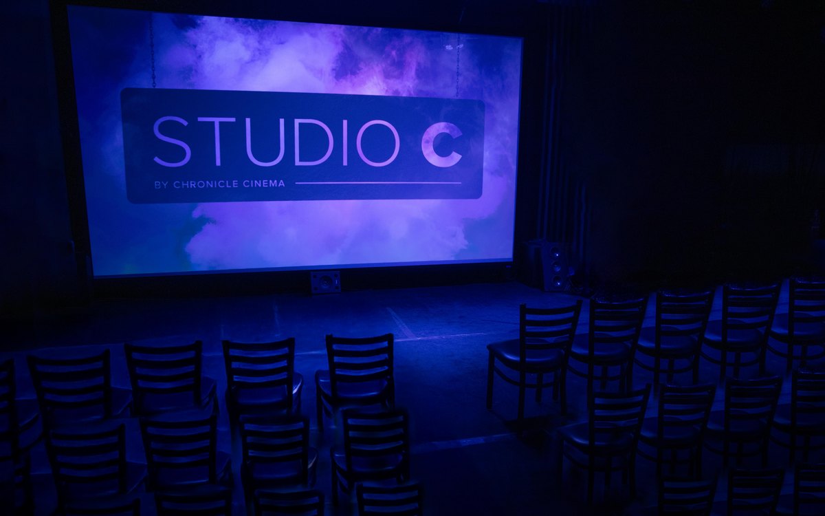 The screening room at Studio C with a projector and seating.