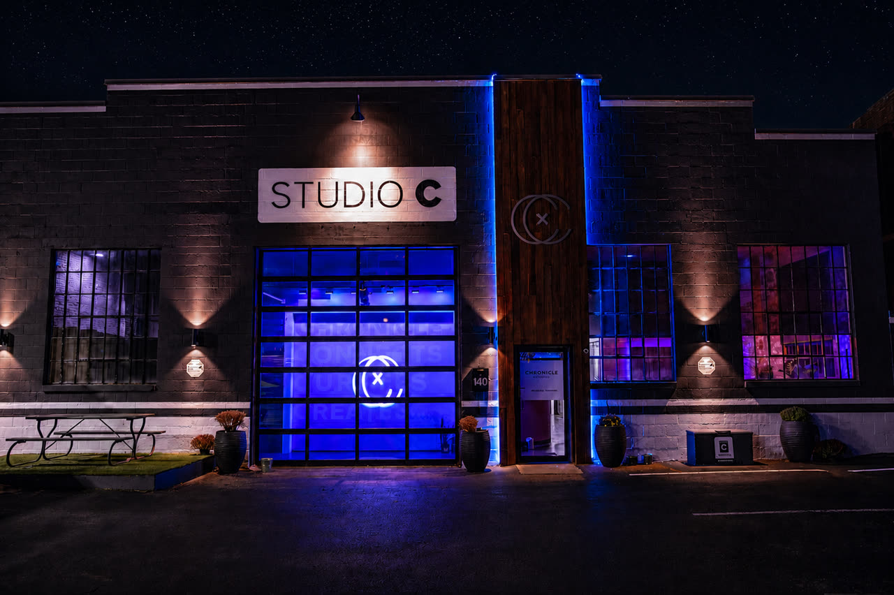 Studio C exterior at night with blue LED lighting, a glass garage door, and wood trim.