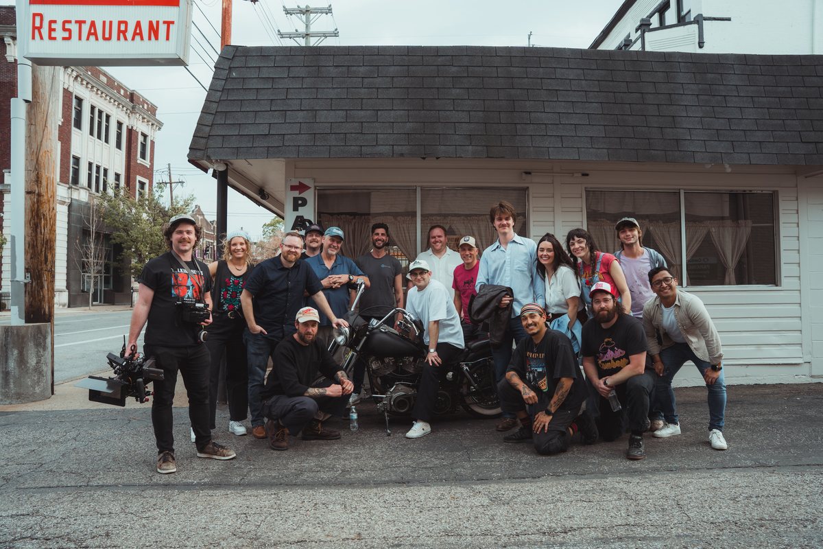 The full cast and crew of the Free Bird music video on set in Kentucky outside a diner surrounding the motorcycle.