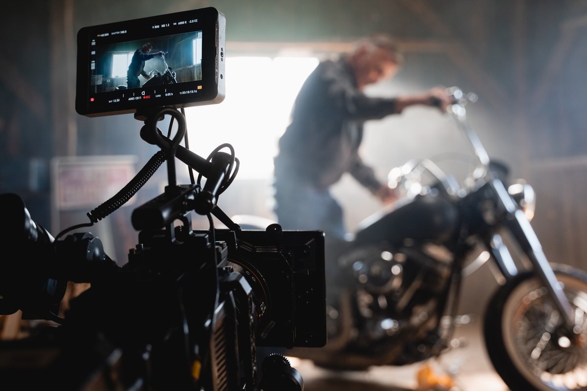 An Arri Alexa films a silhouetted rider preparing a vintage motorcycle in a smoky garage.