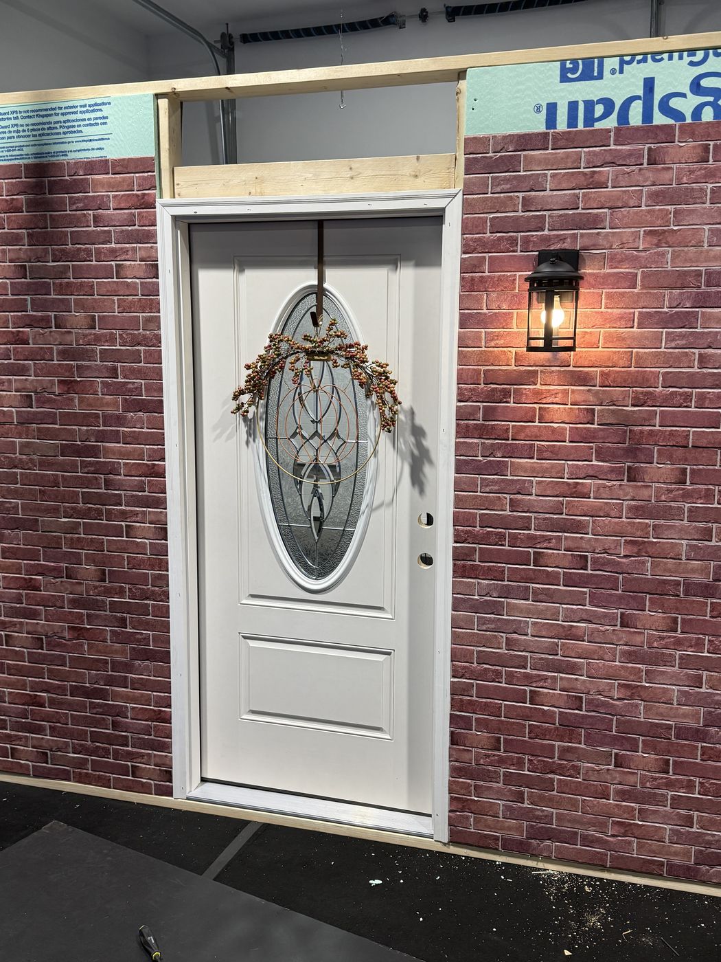The finished porch: brick facade, lantern, and the front door dressed for Halloween.